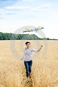 Mother and daughter run in a wheat field with a kite in the summer. Well-planned and active weekend. Happy childhood.
