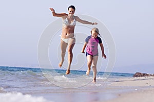 Mother and daughter running at the beach