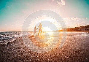 Mother and daughter running inside the water on tropical beach - Mum playing with her kid in holiday vacation next to the ocean -