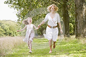 Mother and daughter running on woodland path