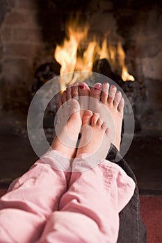 Mother and daughter's Feet warming at a fireplace