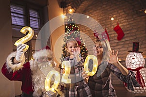Mother, daughter and Santa holding illuminative numbers 2020