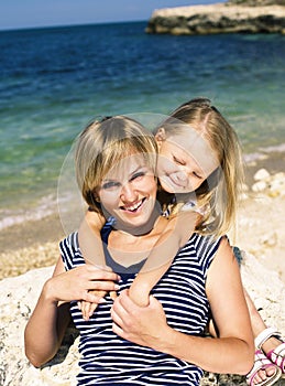 mother with daughter at sea cost together, happy real family smi