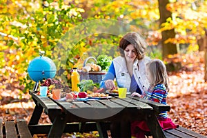 Mother and daughter set table for picnic in autumn