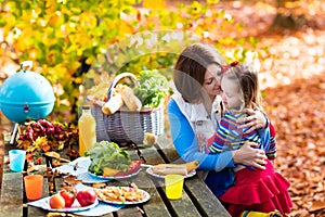 Mother and daughter set table for picnic in autumn