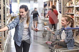 Mother and daughter shopping in supermarket choosing products