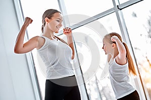 Mother and daughter showing strong hands in gym