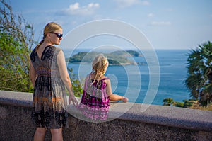 Mother and daughter at side of tropical island view piont