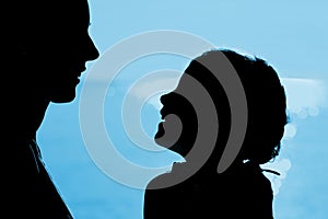 Mother with daughter silhouette near sea