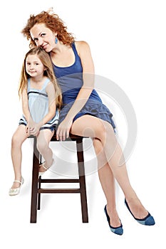 Mother and daughter sit on stool
