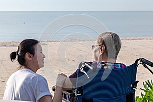 Mother and daughter sit together in front of the beach looking at each other