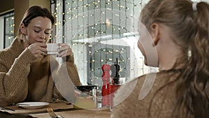 mother and daughter sit together in a restaurant and drink tea, talk