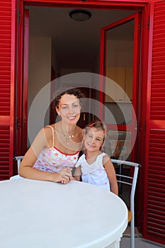 Mother with daughter sit on verandah