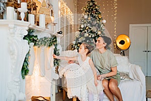 mother and daughter sitting on couch at Christmas tree and fireplace with socks