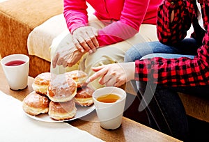 Mother and daughter sitting on couch with donuts and tea on table