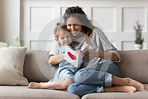 Mother and daughter sitting on couch holding postcard reading wishes