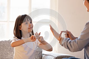 Mother daughter sitting on couch nonverbal communicating with sign language