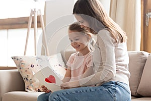 Mother and daughter sitting on couch reading wishes on postcard