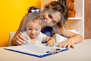 Mother and daughter sitting at the desk doing homework together.