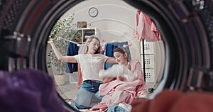 Mother and daughter are sitting on the laundry room floor playing together tossing clothes up. A view of the bathroom