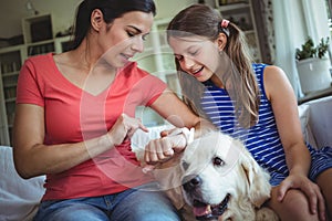 Mother and daughter sitting with pet dog and checking the smart watch