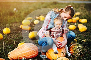 Mother and daughter sitting on pumpkins