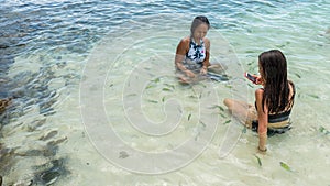 Mother and daughter sitting in sea at beach