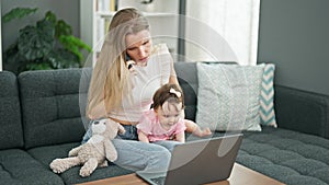 Mother and daughter sitting on sofa talking on smartphone using laptop stressed at home