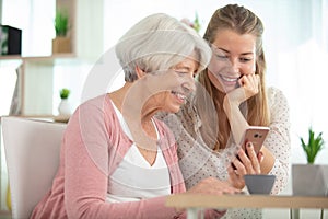 mother with daughter sitting on sofa using social media