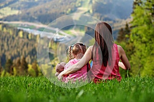 Mother and daughter sitting on top of a mountain. The concept of