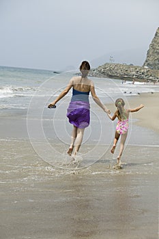 Mother and daughter skipping on beach