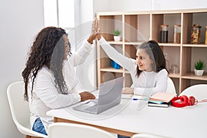 Mother and daughter smiling confident high five with hands raised up at home