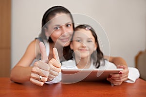 Mother and daughter smiling and showing thumb