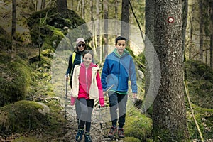Mother with daughter and son, hiking in the forest. Marked trail with blazers