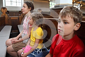 Mother, daughter and son sit on bench in Church