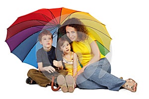 Mother, daughter and son with umbrella sitting
