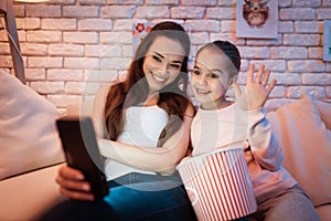 Mother and daughter speaking with father on phone at night at home.