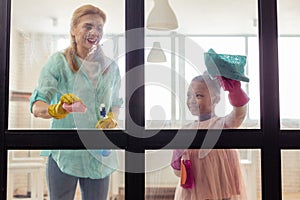 Mother and daughter spending time together while cleaning the flat