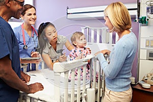 Mother And Daughter With Staff In Pediatric Ward Of Hospital