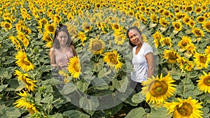 Mother and daughter standing in a field and posing  while surrounded by sunflowers