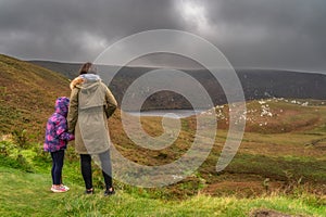 Mother and daughter standing and looking at lake, Lough Bray in Wicklow Mountains