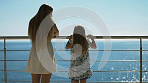 Mother and daughter standing on the outdoor terrace overlooking the sea