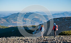 Mother and daughter standing on the ridge of the mountain