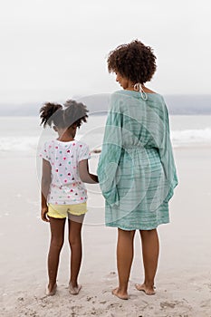 Mother and daughter standing together on the beach