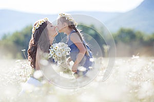 Mother and daughter in summer field of blooming daisies