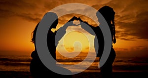 Mother, daughter and sunset at beach with heart gesture for bonding, summer and vacation with happiness. Parent, kid and