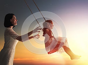 Mother and daughter swinging on swings