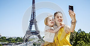 Mother and daughter taking selfie with digital camera in Paris