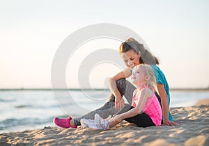Mother and daughter talking and sitting on the beach