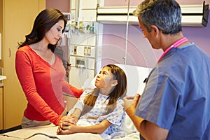 Mother And Daughter Talking To Consultant In Hospital Room